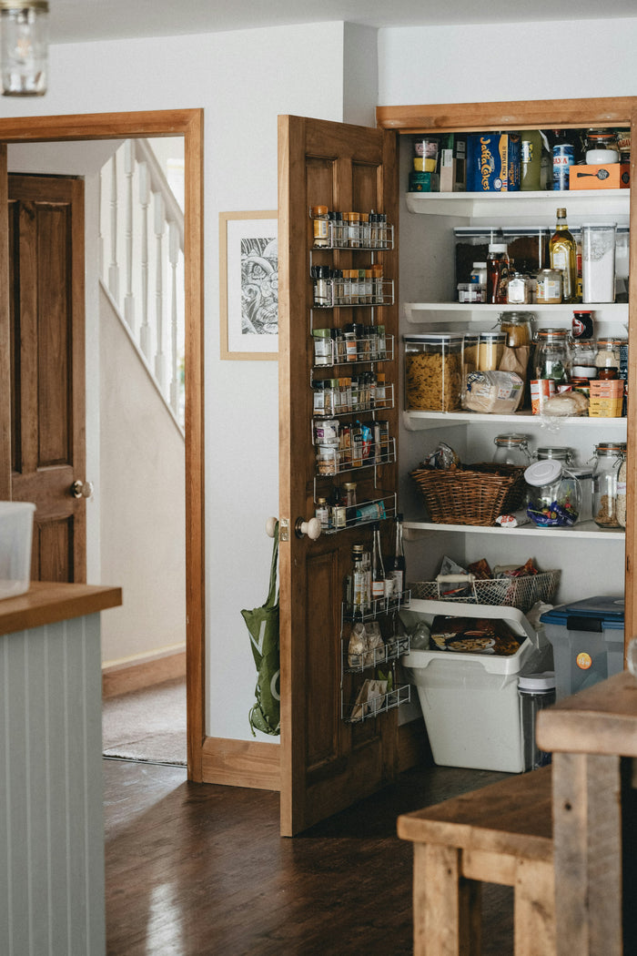 Warm wooden pantry shelves with glass bottles in natural light, heritage kitchen aesthetic