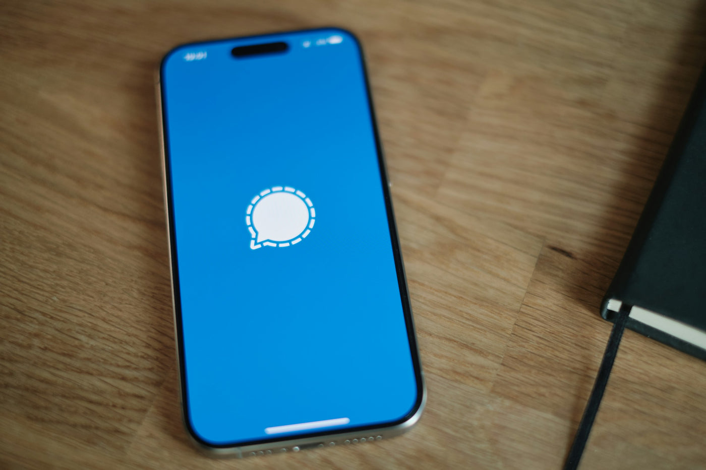 Smartphone resting on a warm wooden table, editorial home crop
