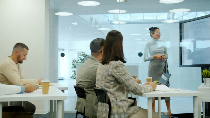 Woman presenting to colleagues in a modern conference room using a digital board