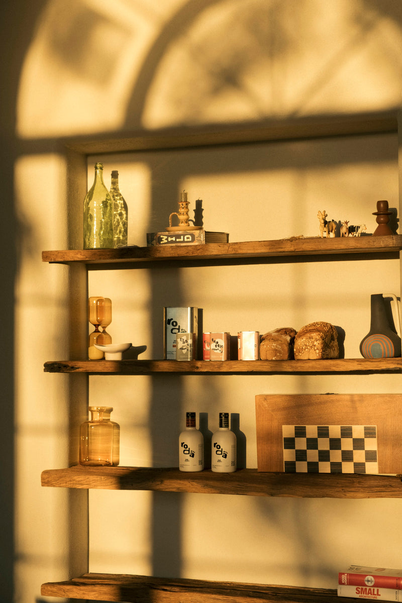 Warm wooden shelves with glass jars and bottles in golden hour light, Hamptons kitchen aesthetic