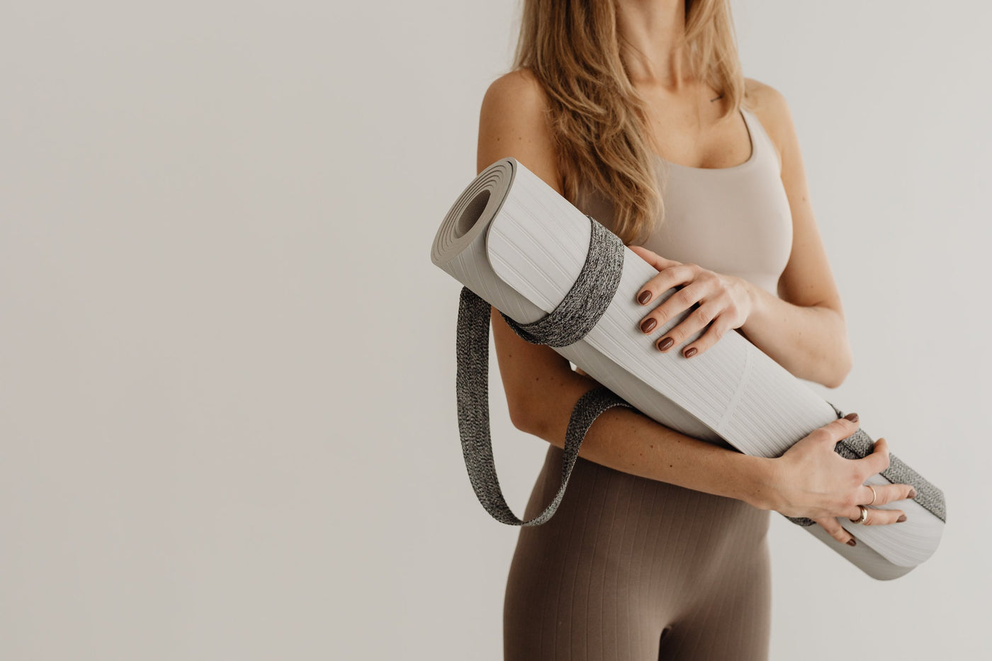Woman in a brown workout outfit exercising on a yoga mat at home in warm natural light